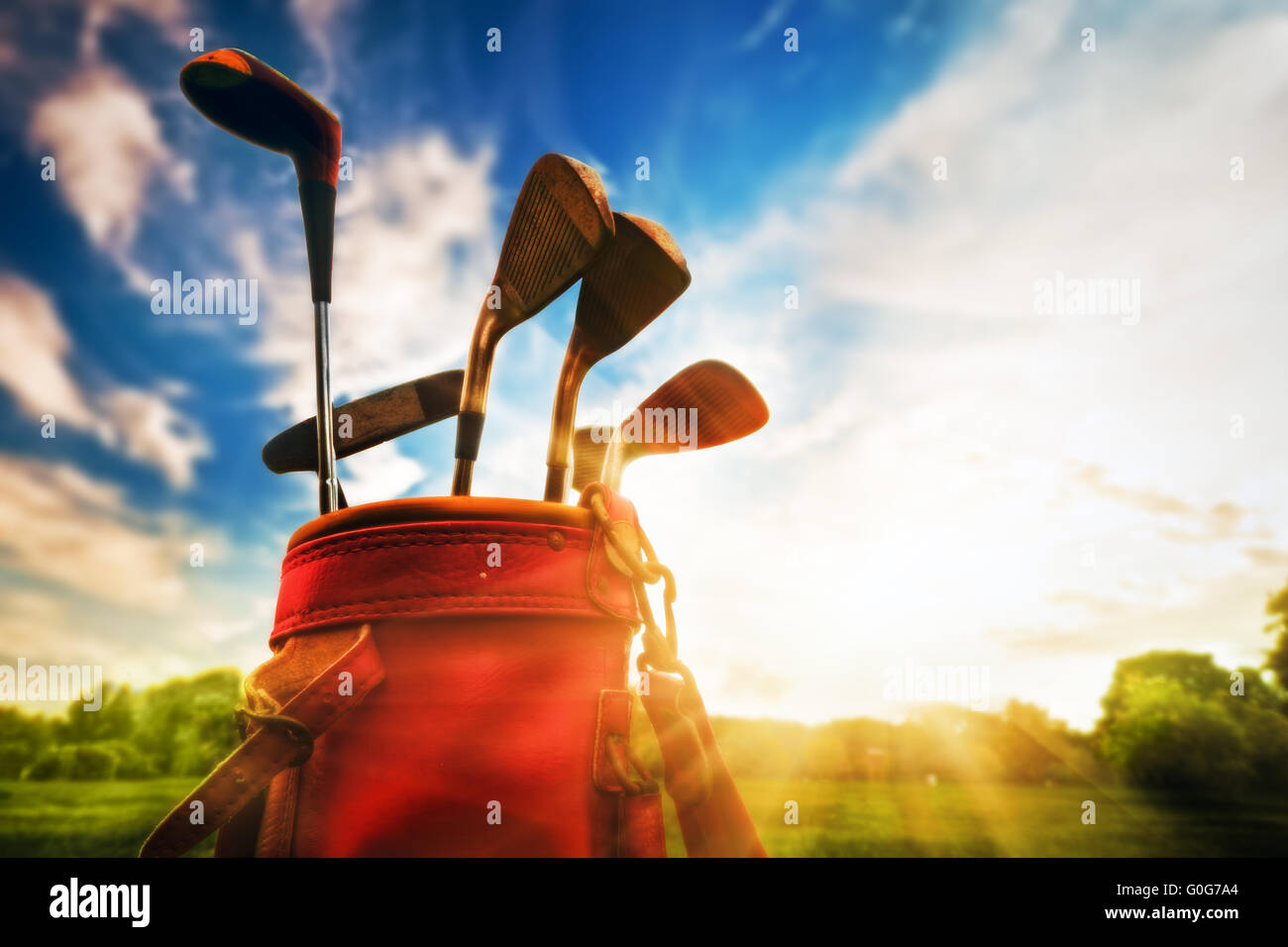 Golf equipment. Professional golf clubs in a leather baggage at sunset