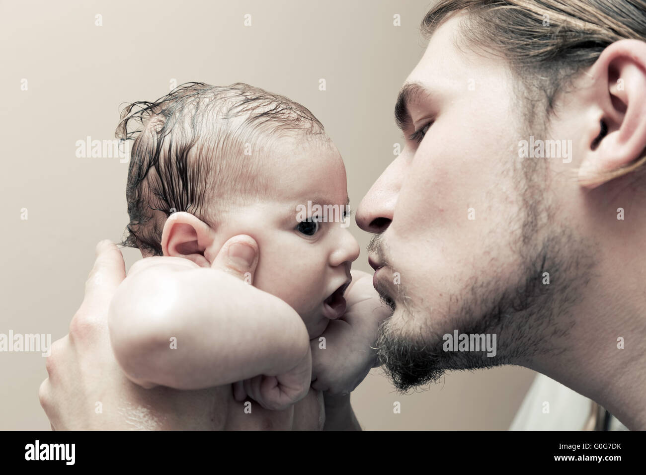 Father with his young baby cuddling and kissing him on cheek. Parenthood Stock Photo