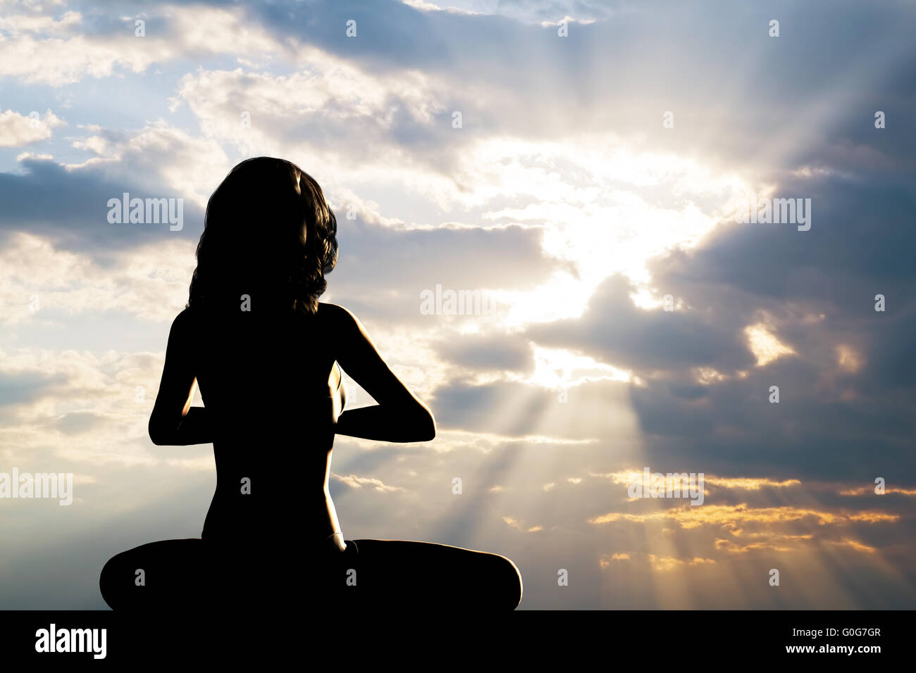 A silhouette of a woman sitting in yoga position Stock Photo