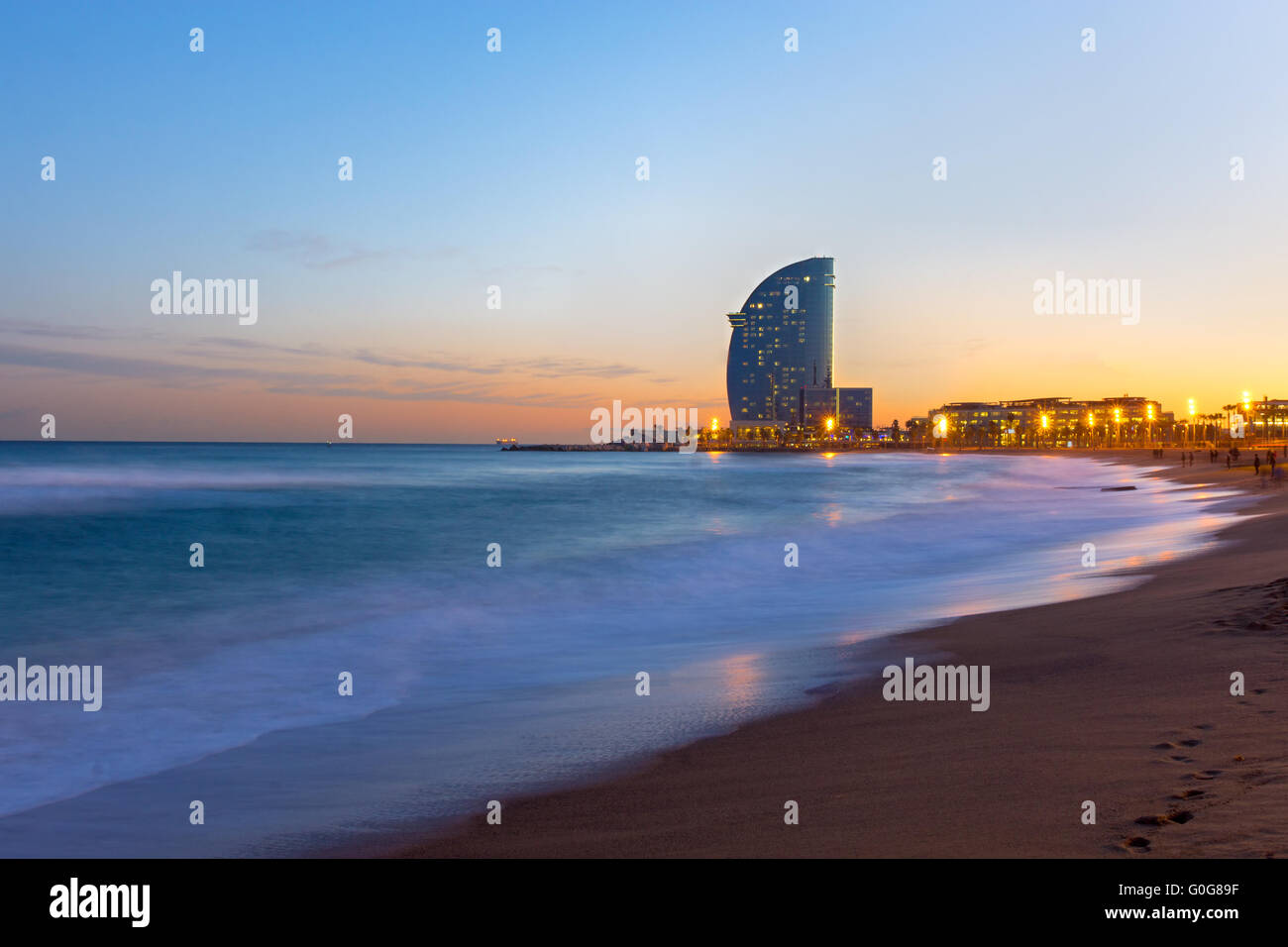 The beach of Barcelona with a modern skyscraper at sunset Stock Photo