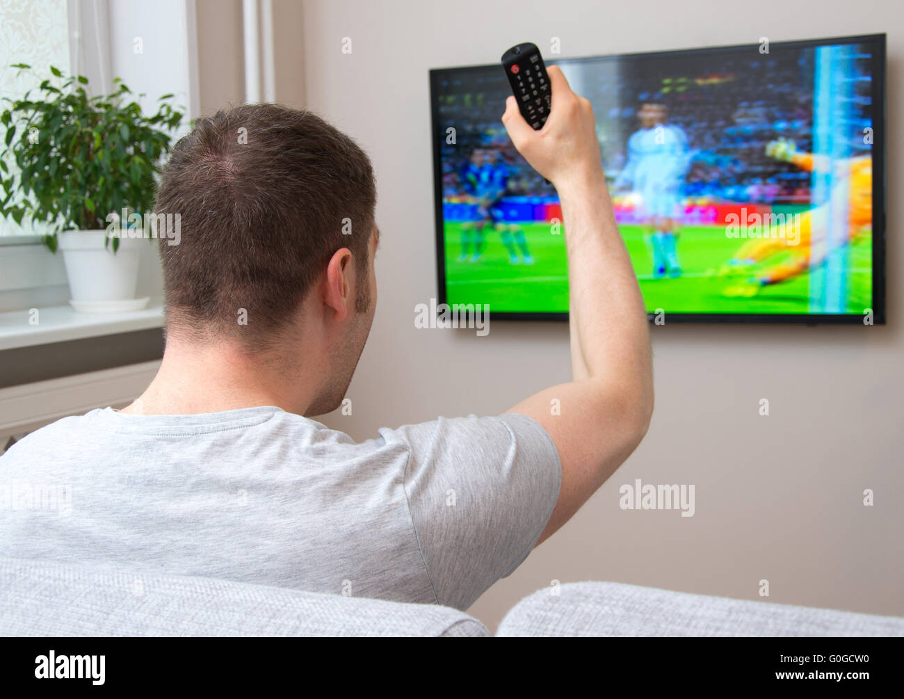 Man watching football match on television at home Stock Photo - Alamy