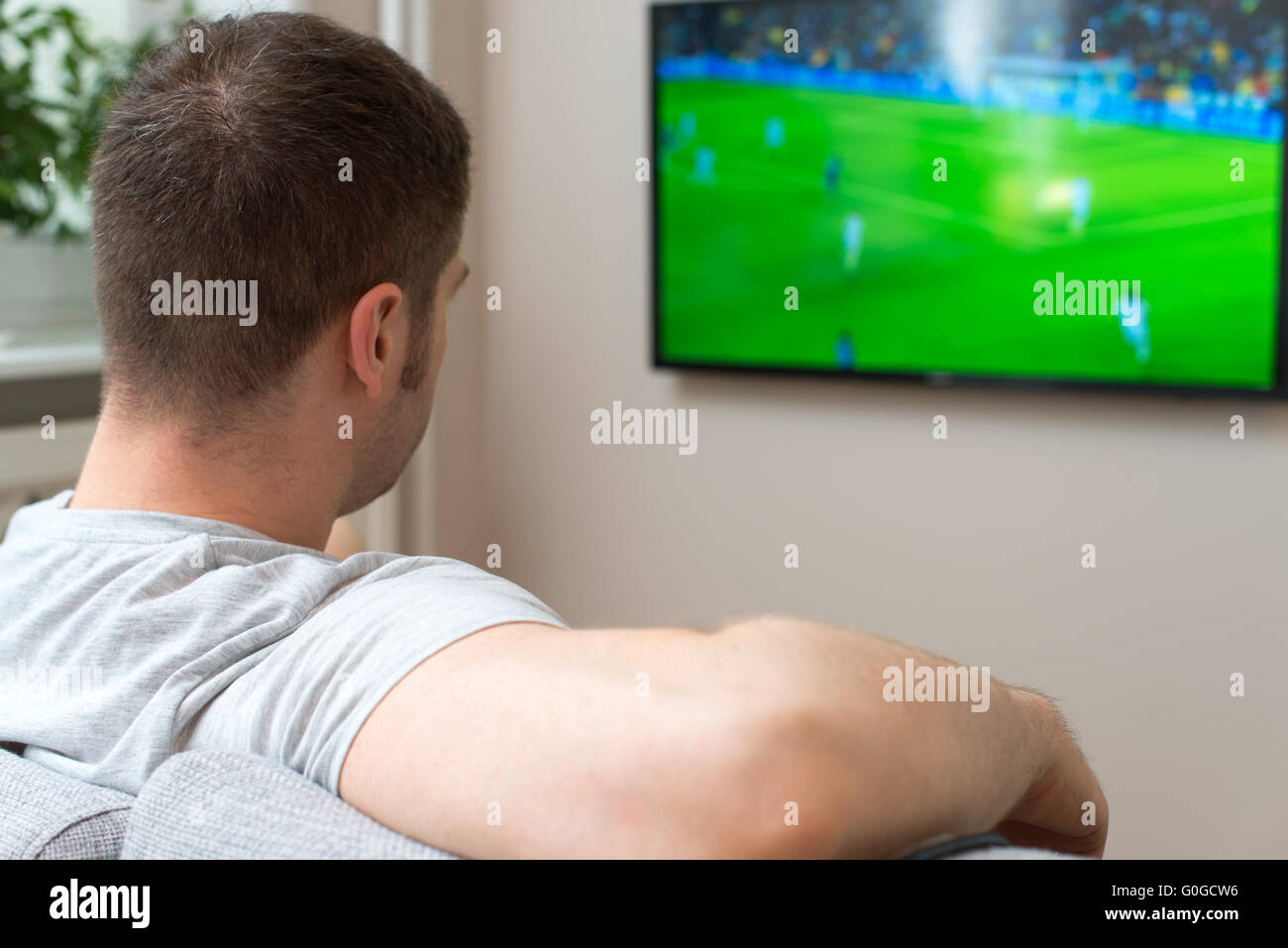 Man watching football match on television at home Stock Photo - Alamy
