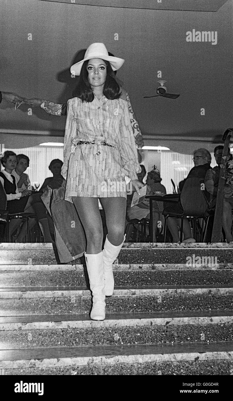 Sixties, black and white photo, people, fashionshow, young woman 20 to 25 years on a staircase, long-haired, minidress, hat, high boots Stock Photo