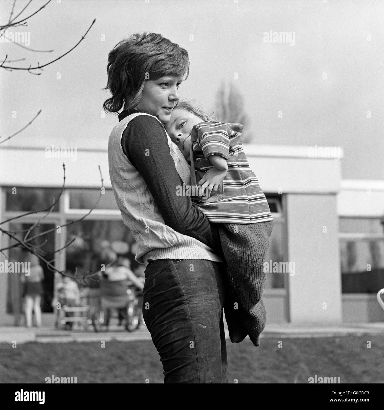 Seventies, black and white photo, people, physical handicap, fostress 20 to 25 years carries a handicapped girl 3 to 4 years on her arms, Monika, Carola, Special School Alsbachtal, D-Oberhausen, D-Oberhausen-Sterkrade, Ruhr area, Lower Rhine, Rhineland, North Rhine-Westphalia, NRW Stock Photo