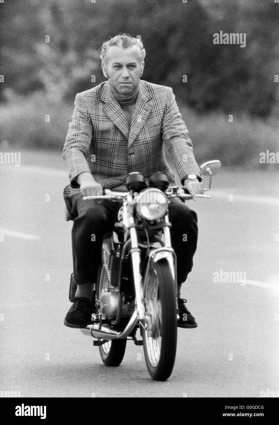 Seventies, black and white photo, people, man 40 to 50 years driving on a country road by motorbike Stock Photo