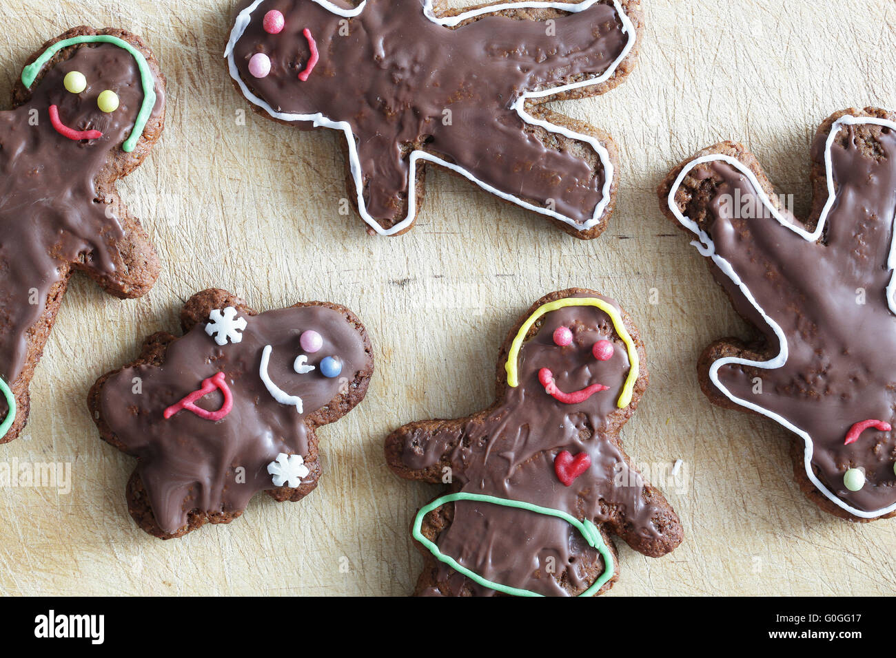 Handmade decorated gingerbread people lying on wooden table. Christmas Stock Photo