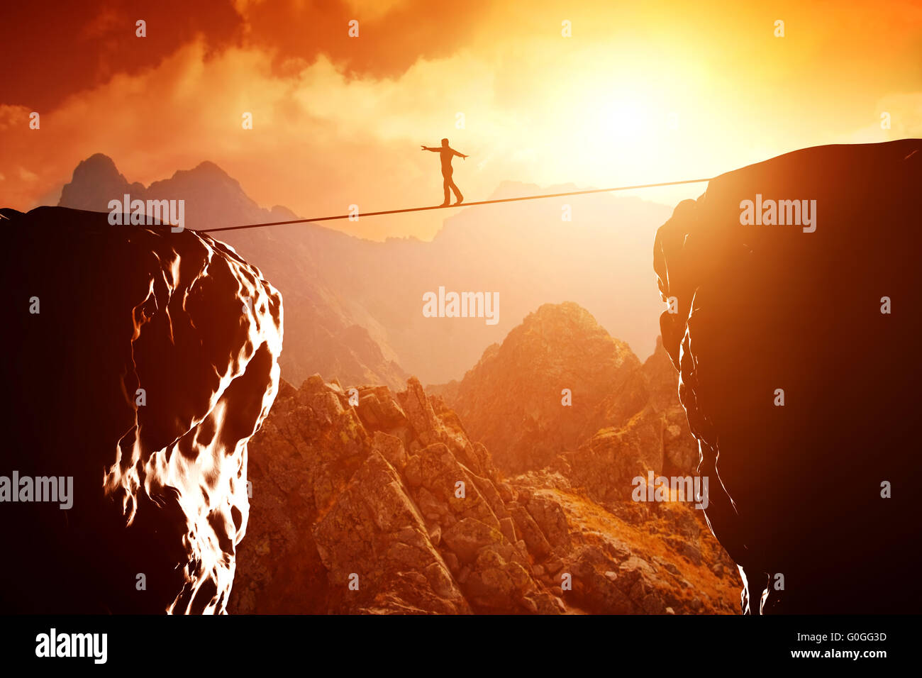 Man walking and balancing on rope over precipice in mountains at sunset. Concept of business Stock Photo