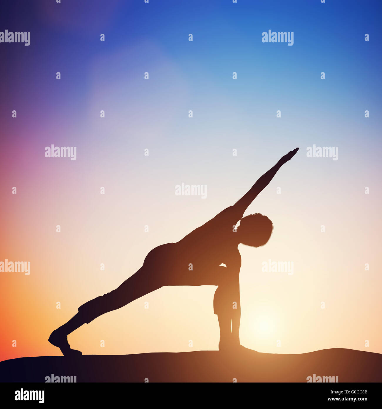 Woman standing in revolved side angle yoga pose meditating at sunset. Zen Stock Photo