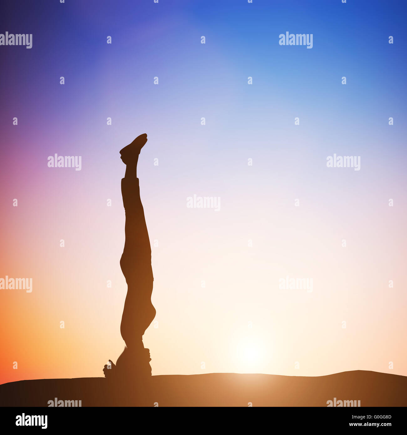 Woman in head stand yoga pose meditating at sunset. Zen Stock Photo