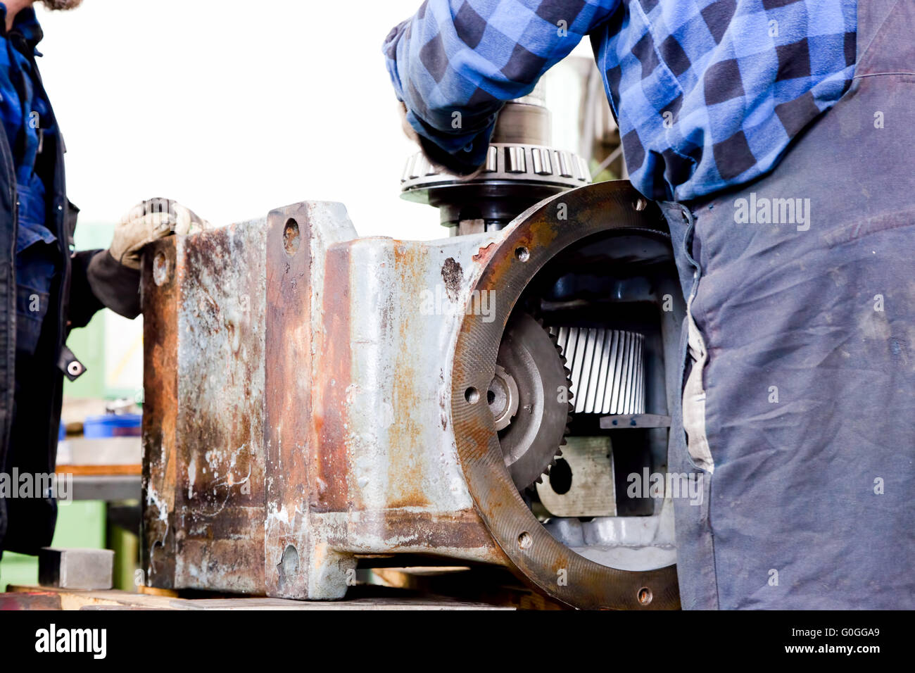 Workers repair, work on old gear element in workshop. Industry Stock Photo