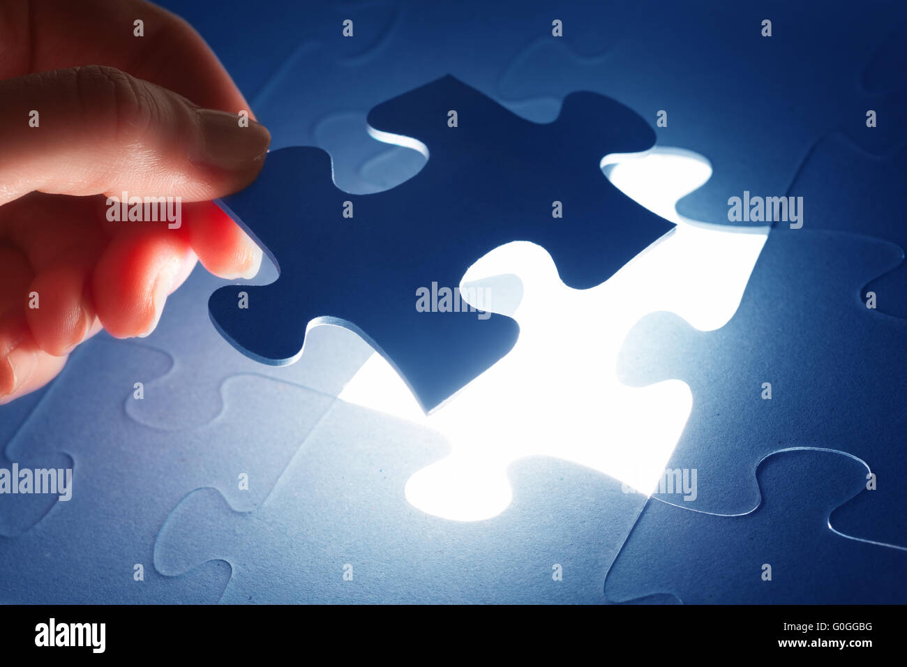 Completing the last piece of jigsaw puzzle. Light glow from empty space. Search for the solution Stock Photo