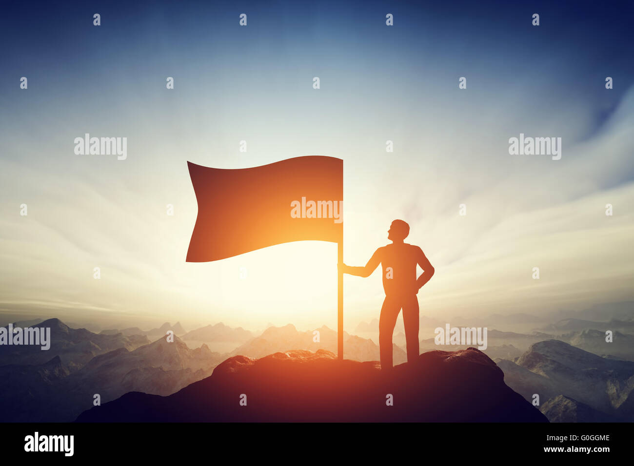 Proud man raising a flag on the peak of the mountain. Challenge, achievement Stock Photo