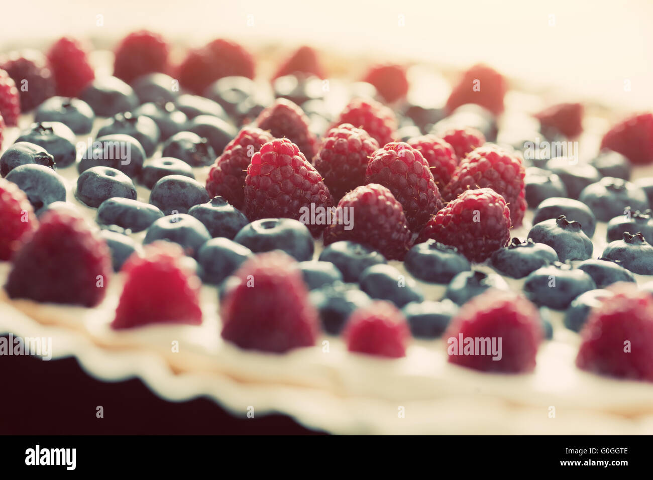 Fruit tart with fresh raspberry and blueberry. Vintage light Stock Photo