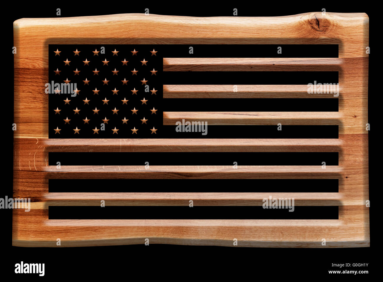 The USA flag cut in a wooden board, plate isolated on black. Stock Photo
