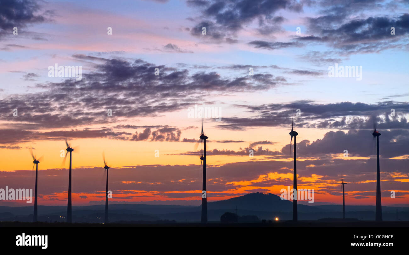 Turning windengines in Germany in front of a dramatic sunset sky Stock Photo