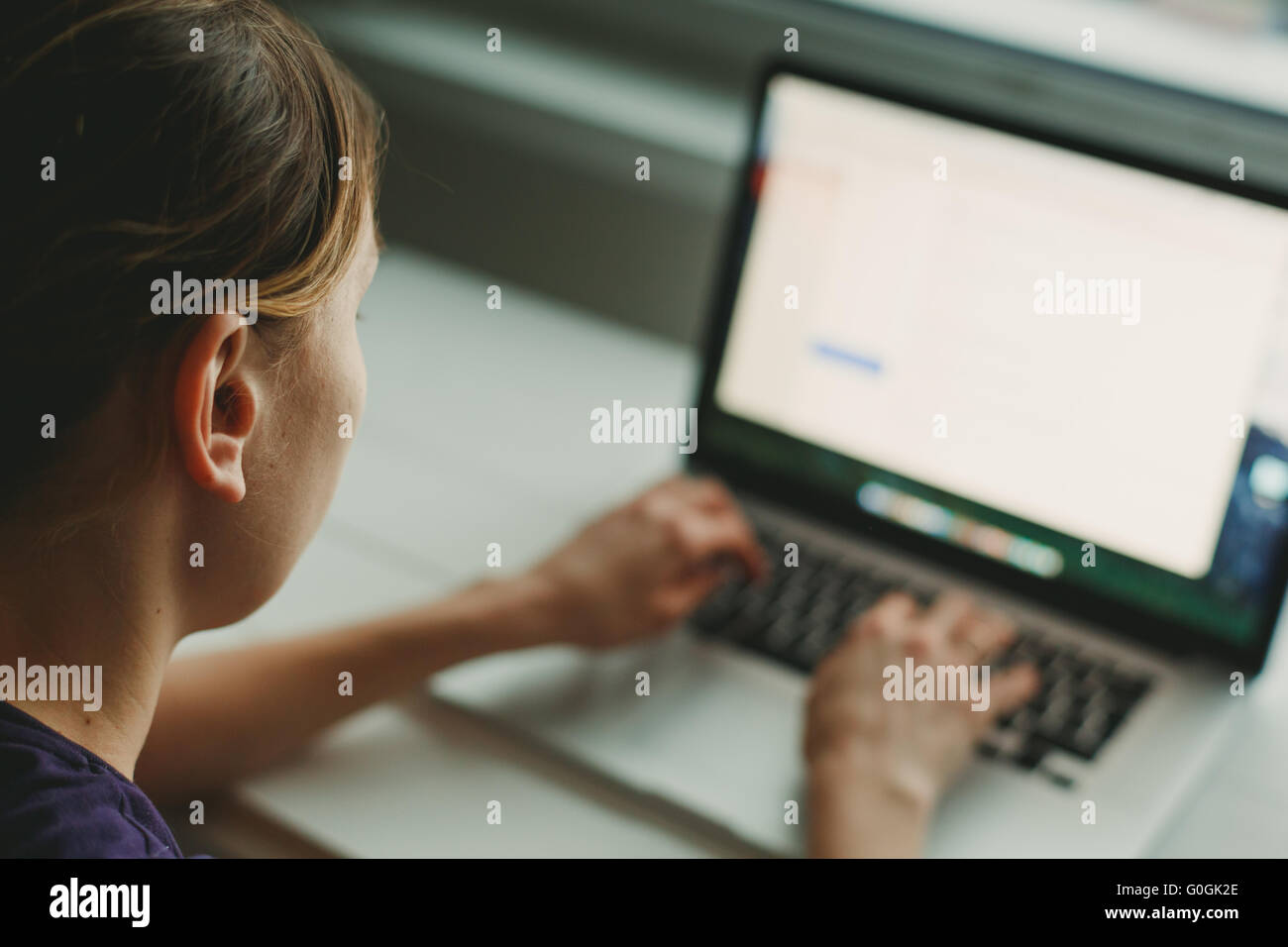 Woman working with laptop placed on wooden desk Stock Photo