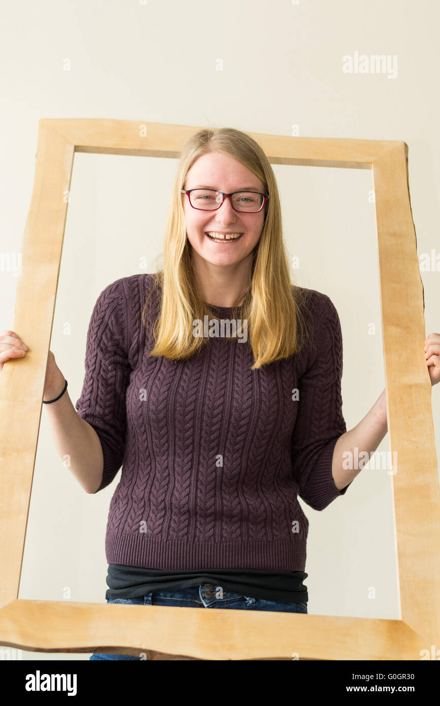 laughing Teenage girl looking through wooden picture frames Stock Photo