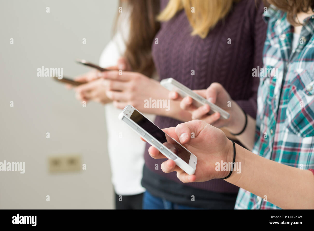 Several teenagers write each sms on her cell phone Stock Photo