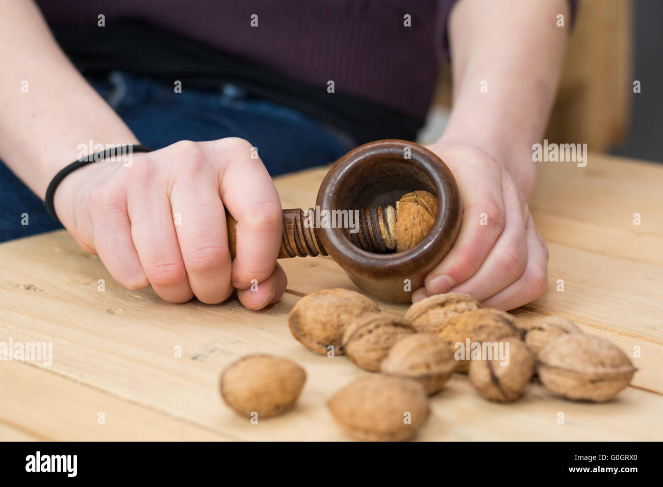 Person cracks on a wooden table walnuts with nostalgic Nutcracker Stock Photo