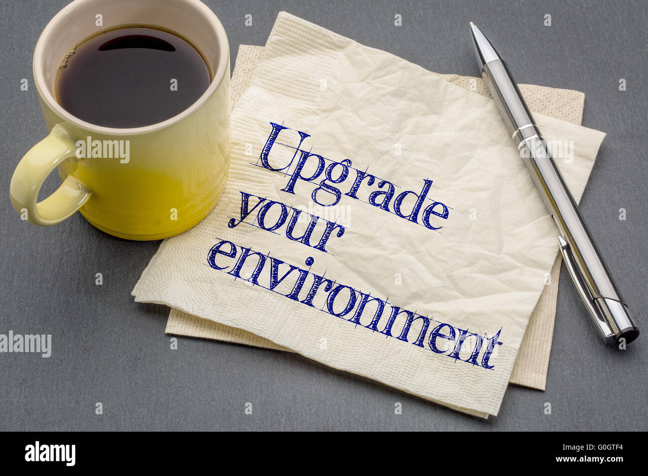 upgrade your environment - handwriting on a napkin with cup of coffee against gray slate stone background Stock Photo
