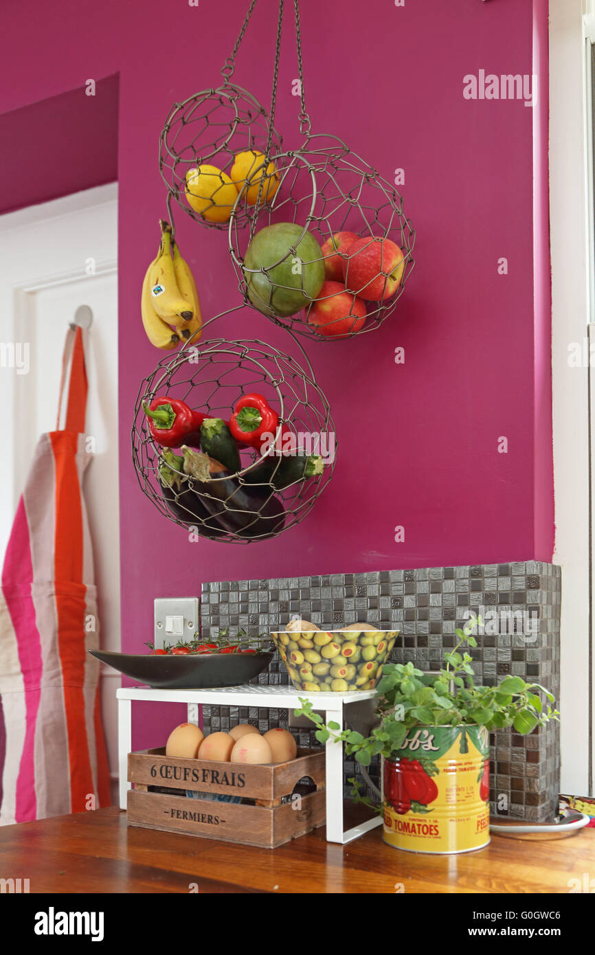 Fruit and vegetables stored in hanging, mesh baskets in a modern
