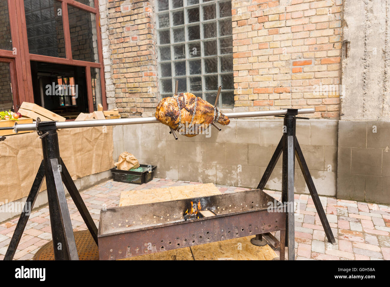 Meat roasting on a spit outdoors over an open barbecue fire on a rotating rotisserie in a