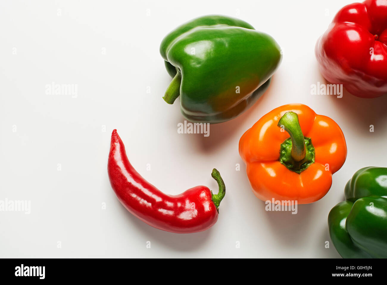 Red, green and orange bell peppers on white background Stock Photo - Alamy