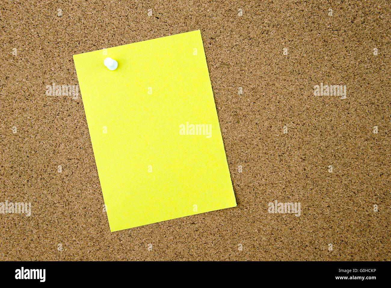 Blank yellow paper note pinned on cork board with white thumbtack, copy ...