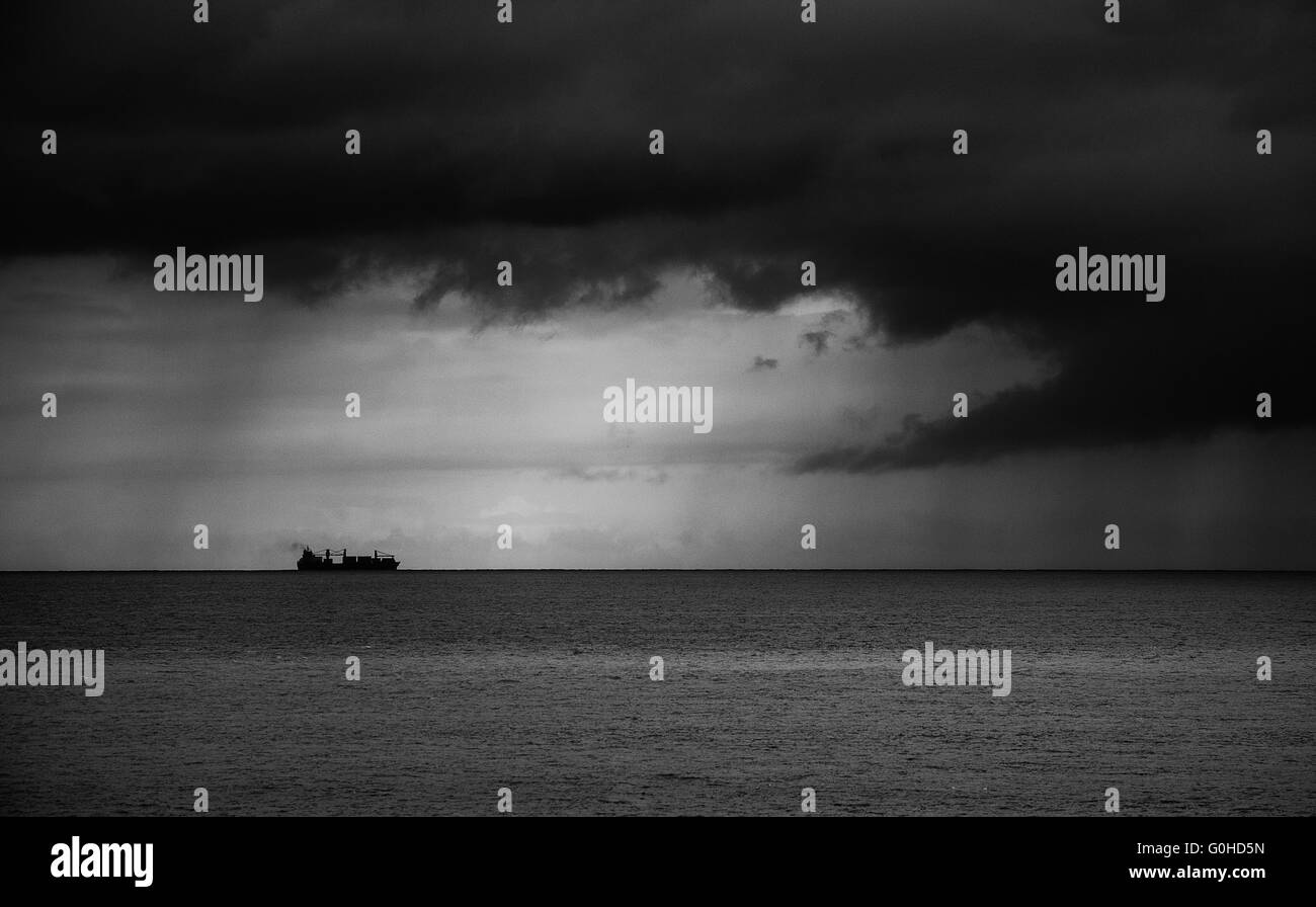 Container ship on the horizon heading toward storm Stock Photo - Alamy