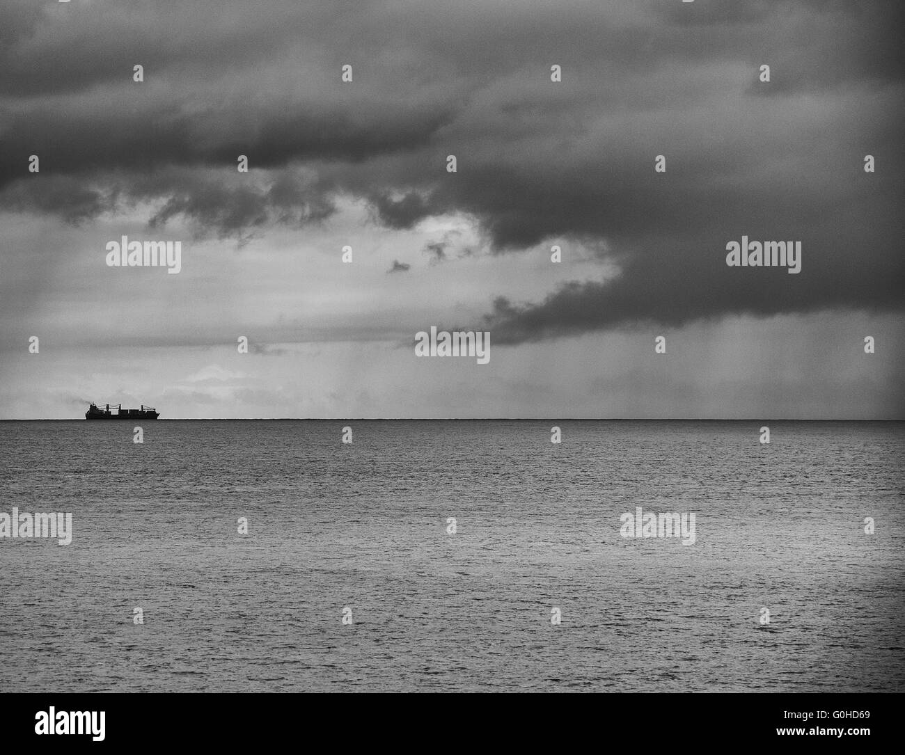 Container ship on the horizon heading toward storm Stock Photo - Alamy