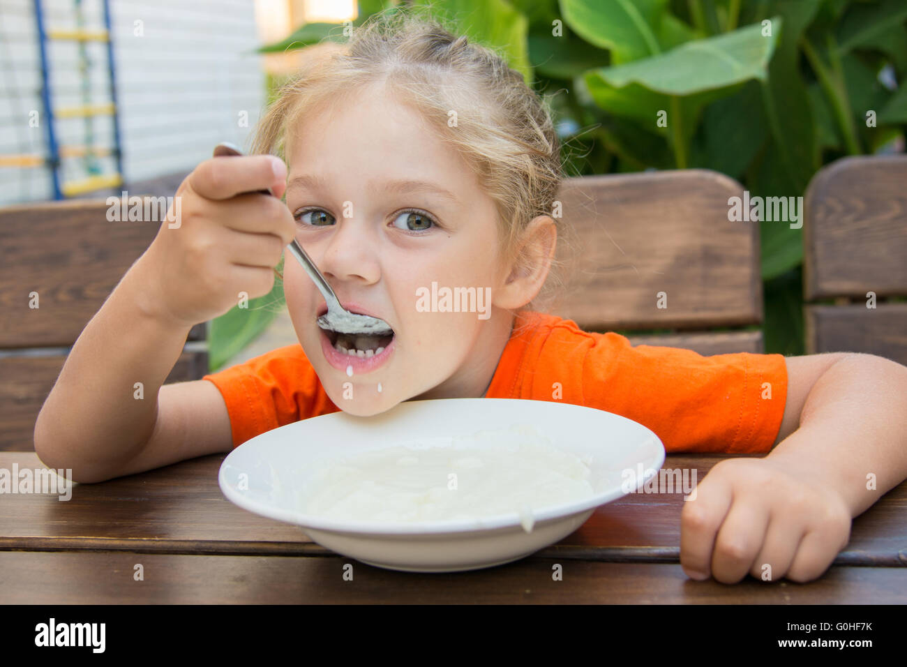 Five-year girl with pleasure eats porridge for breakfast Stock Photo