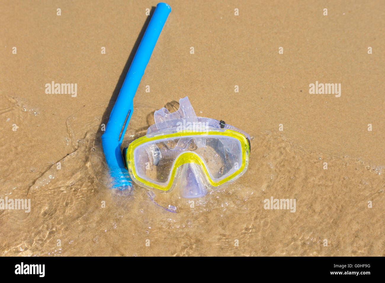 The swimming mask and snorkel to breathe under water, lie on the sand at the waters edge Stock Photo