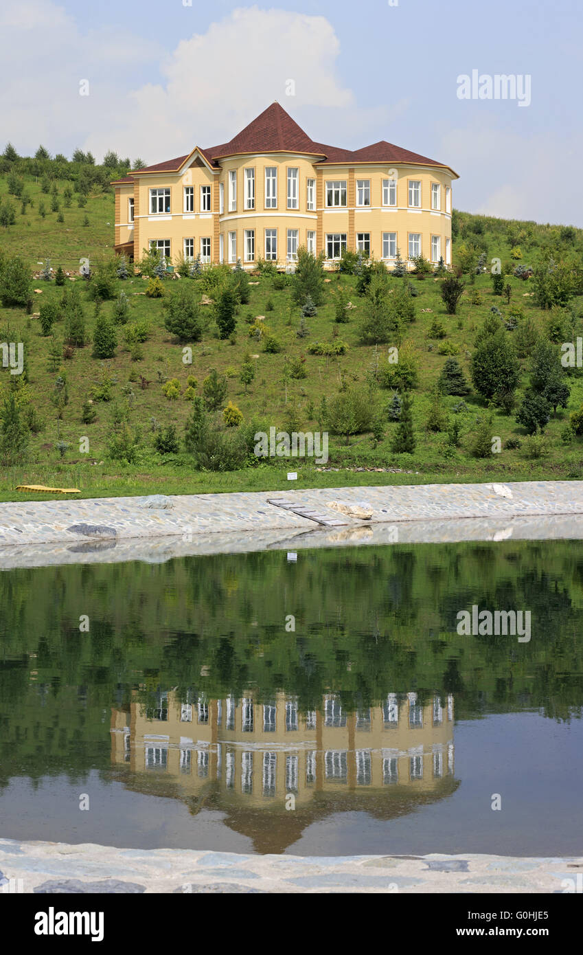 Cottage is reflected in the spring lake. Kennel Arboretum Blooming Valley. Stock Photo
