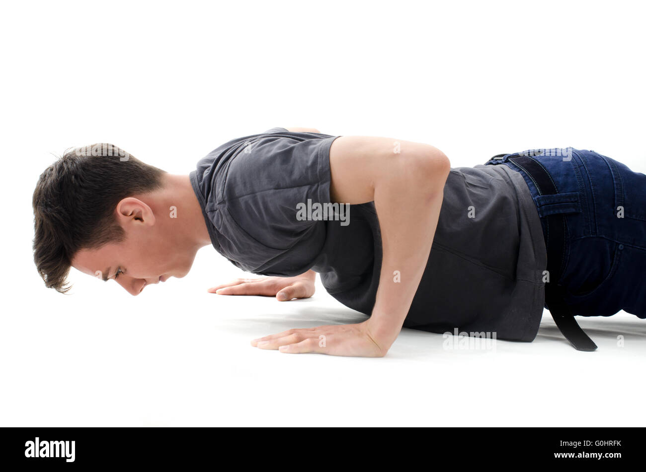Teenager making push ups in jeans and t-shirt isolated on white Stock Photo