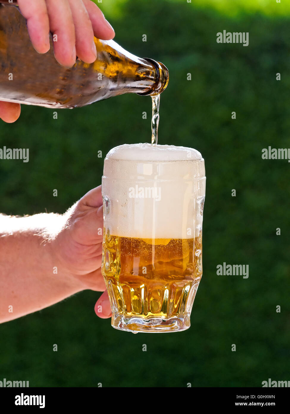 Beer from a beer bottle of beer being poured into glass Stock Photo