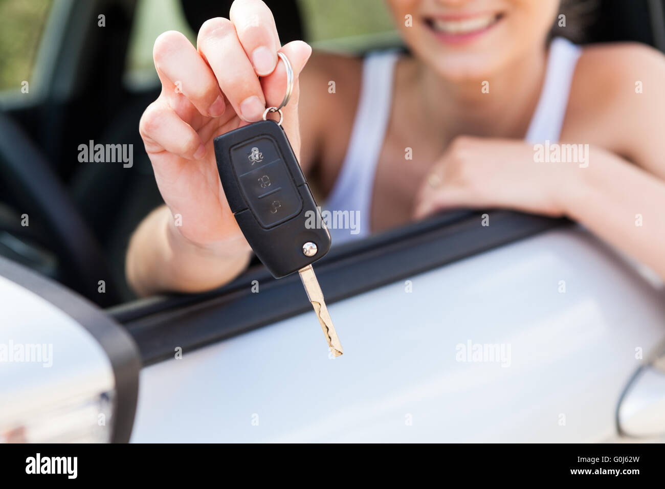 young smiling woman sitting in car taking key Stock Photo