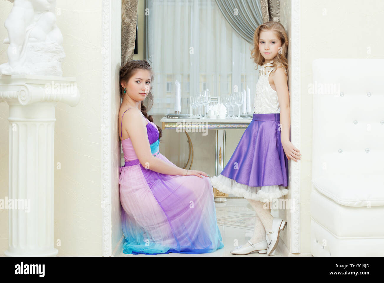 Three young, beautiful, interracial women pose in elegant black dresses aga...
