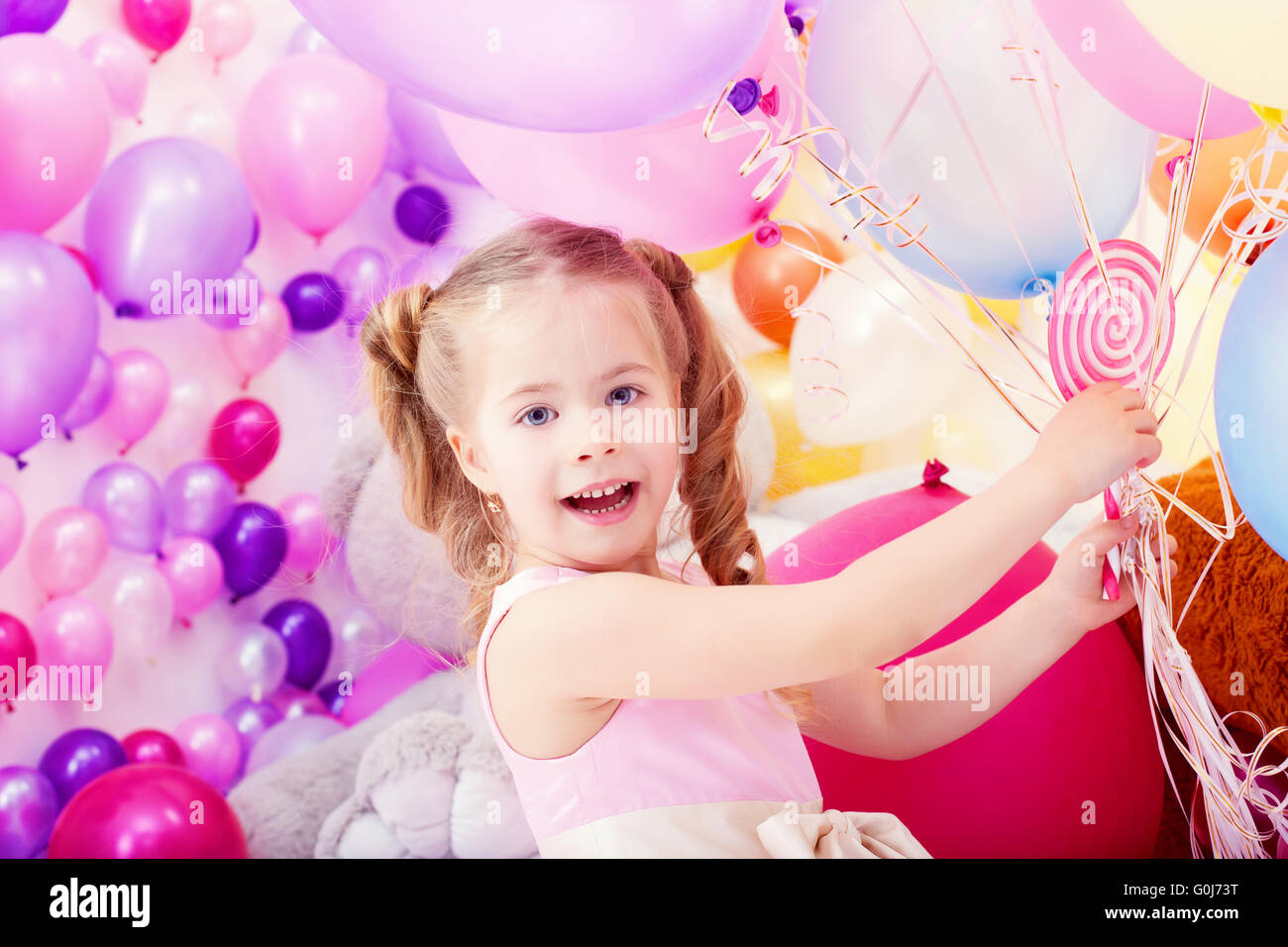 Merry little girl posing with bunch of balloons Stock Photo - Alamy