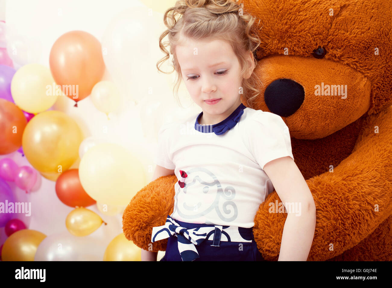 Cute girl posing in embrace with big teddy bear Stock Photo
