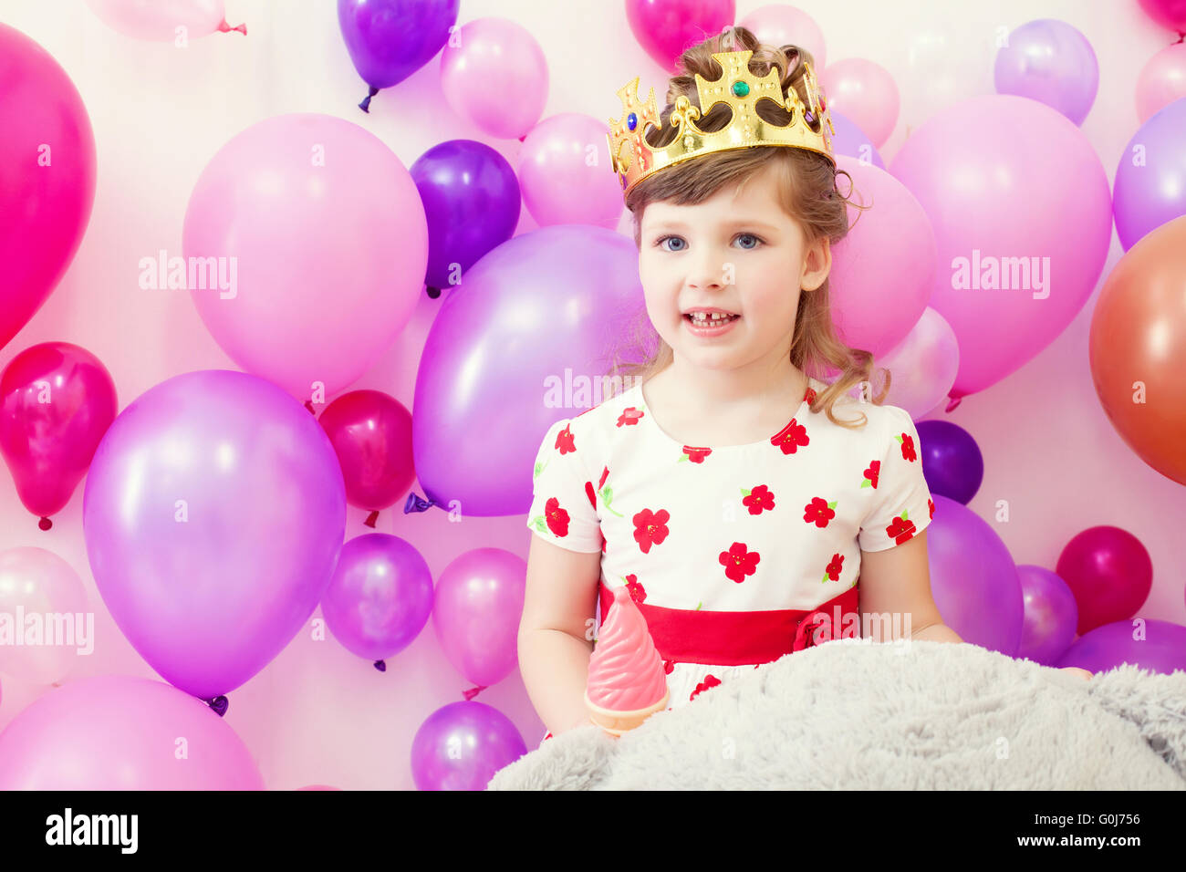Cute girl posing in crown on balloons background Stock Photo