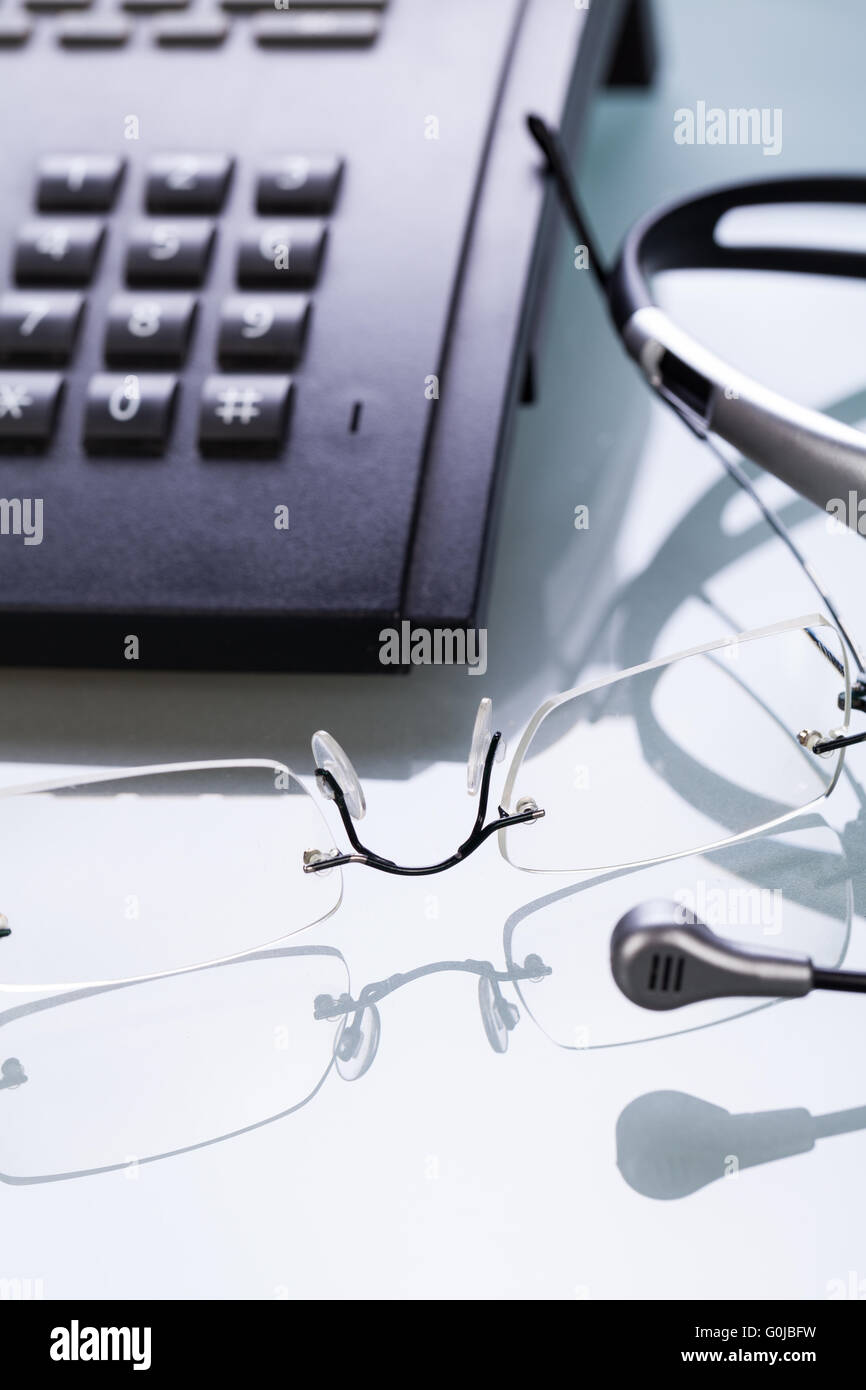 working place office desk table headset glasses telephone Stock Photo