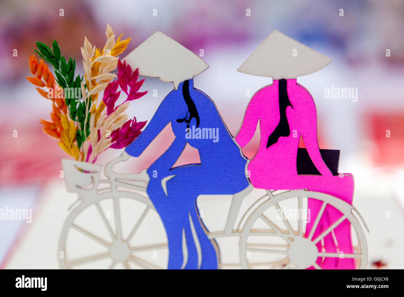 Vietnamese motif of women riding a bike and carrying flowers to the market Stock Photo
