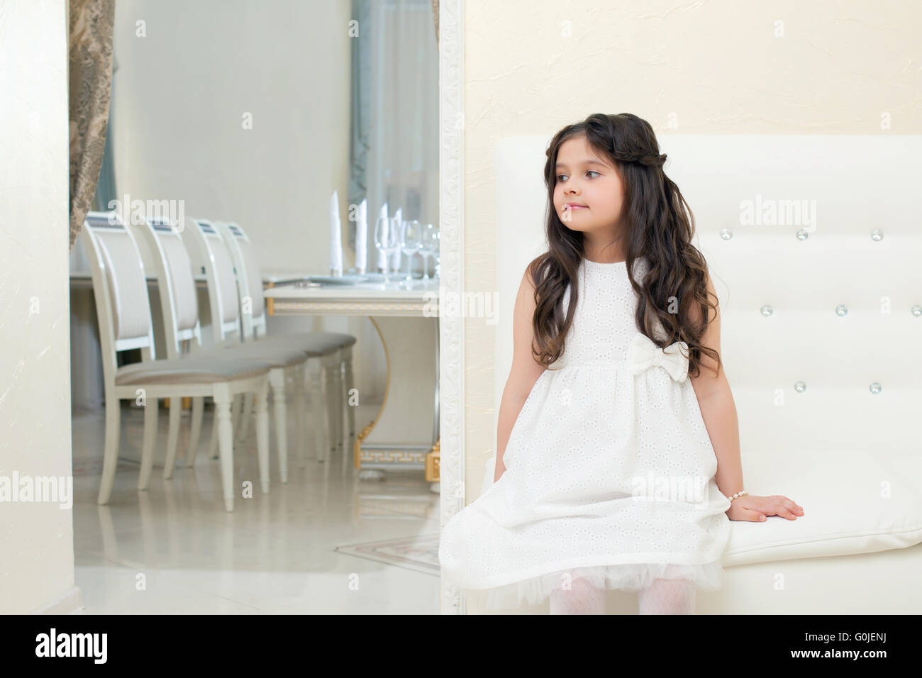 Pretty little girl posing while sitting on couch Stock Photo - Alamy