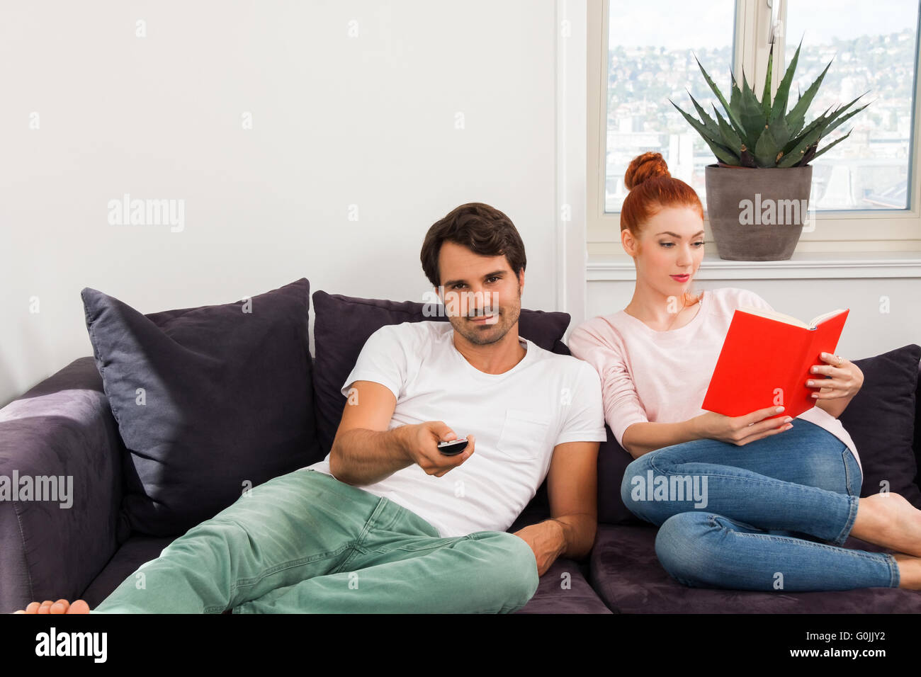Sweet Couple Resting on Couch While Reading a Book Stock Photo