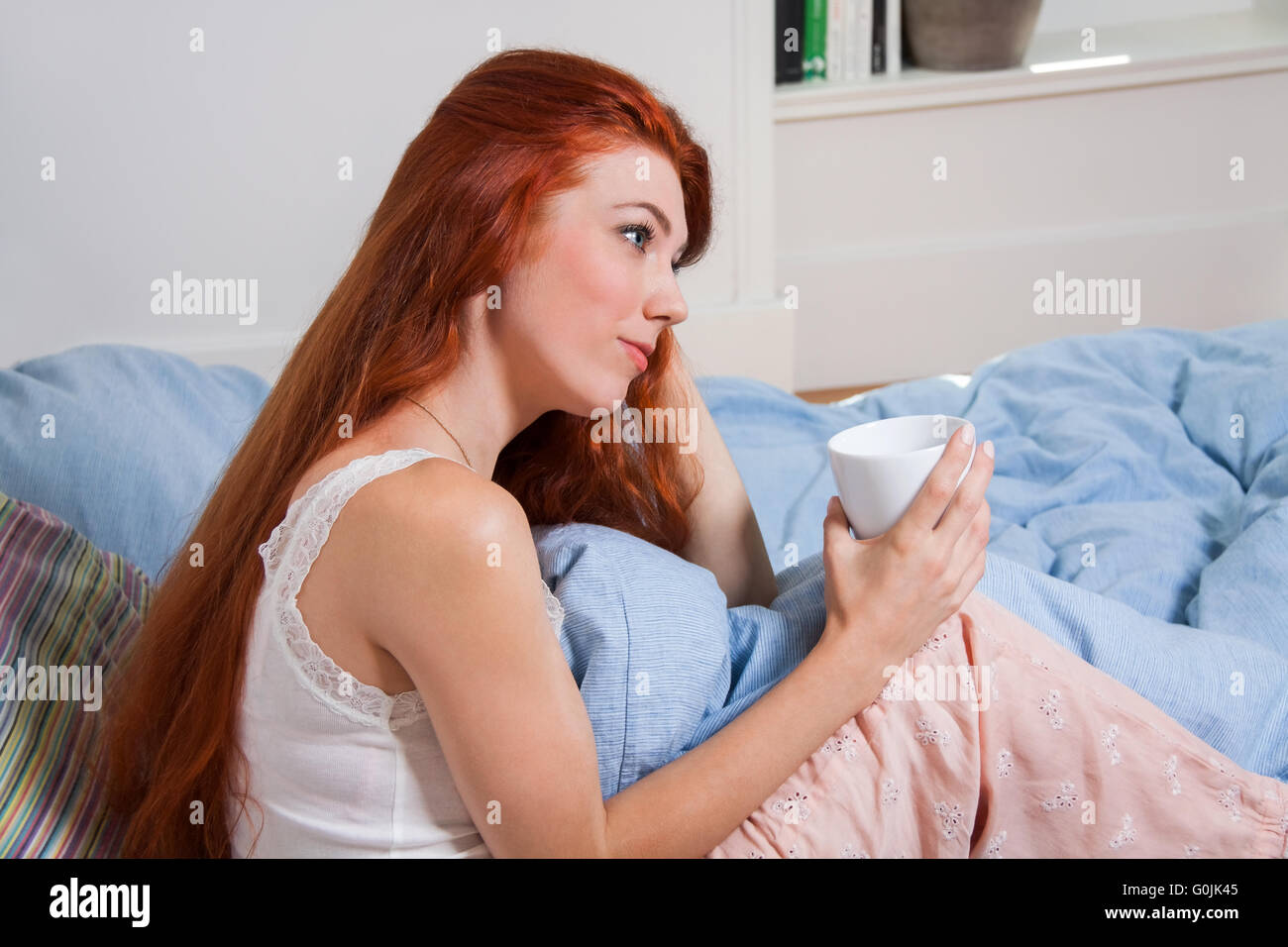 Pensive Woman Having an Early Coffee at her Bed Stock Photo