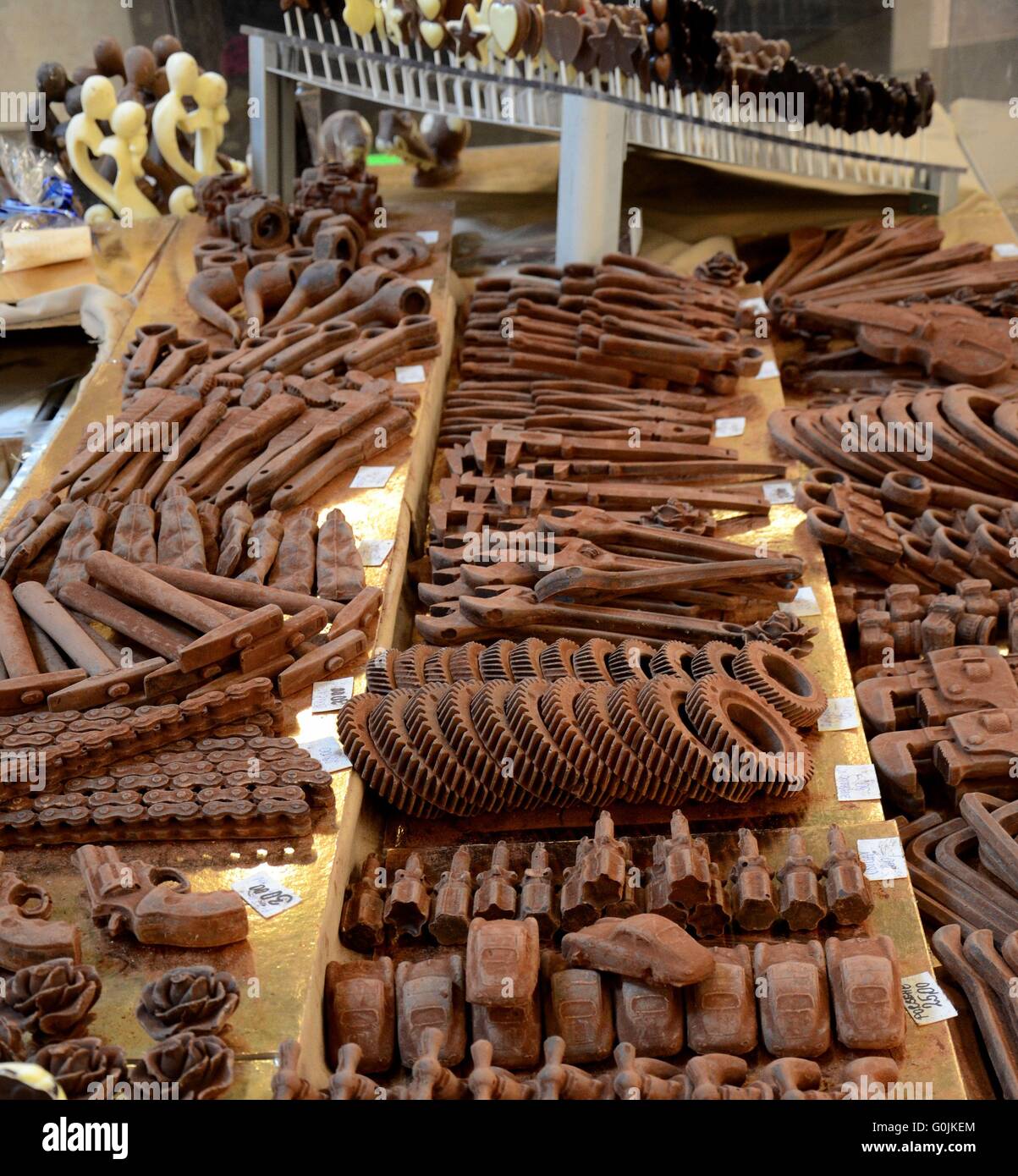 Chocolate sculpture carvings of guns pipes cars chains and couples on display in shelves Stock Photo