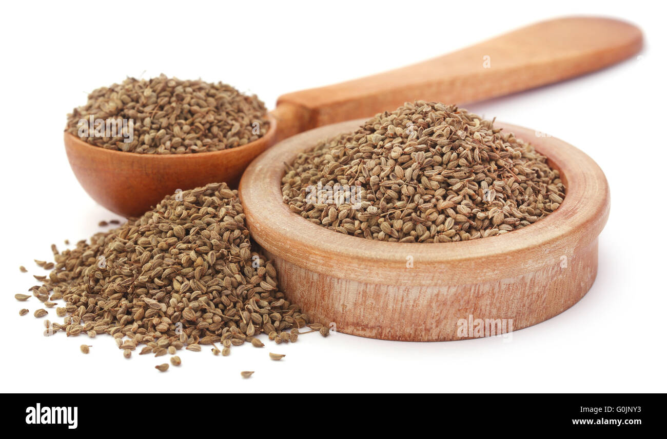 Ajwain seeds in a wooden bowl and spoon over white background Stock