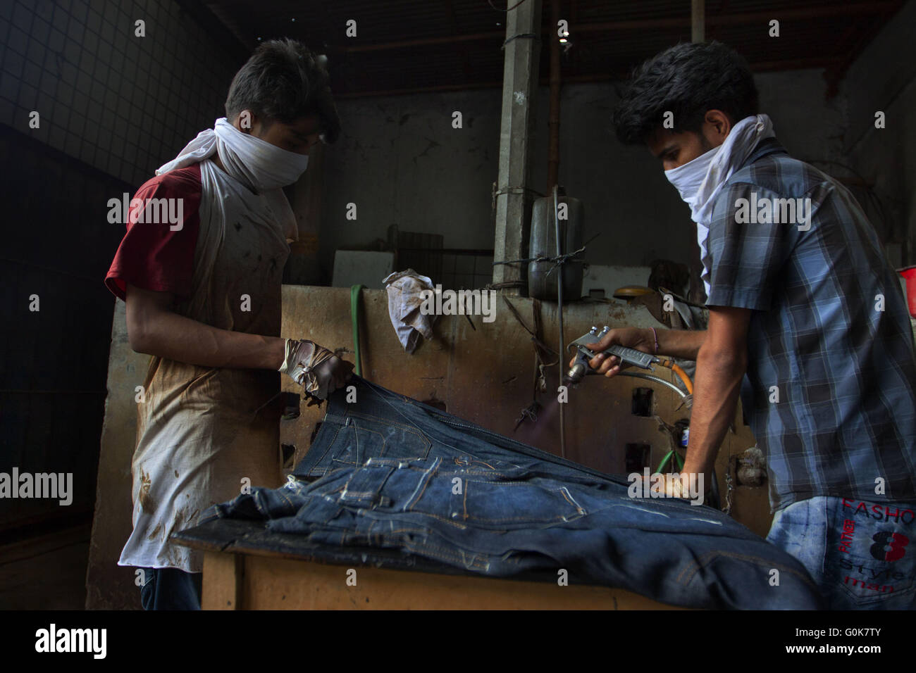 Dhaka, Dhaka, Bangladesh. 3rd June, 2011. Young workers giving jeans a fashionable ''distressed'' look by spraying them with potassium permanganate -- a toxic substance that can cause damage to the nervous system.Bangladesh is one of the leading garment manufacturing countries in the world but most of the factories lack the basic amenities where our garment workers sweat their brows from morning to evening to earn our countries the major portion of our foreign exchange. Improper ventilation, stuffy situation, filthy rooms are the characteristics of the majority of our factories. The owners pr Stock Photo