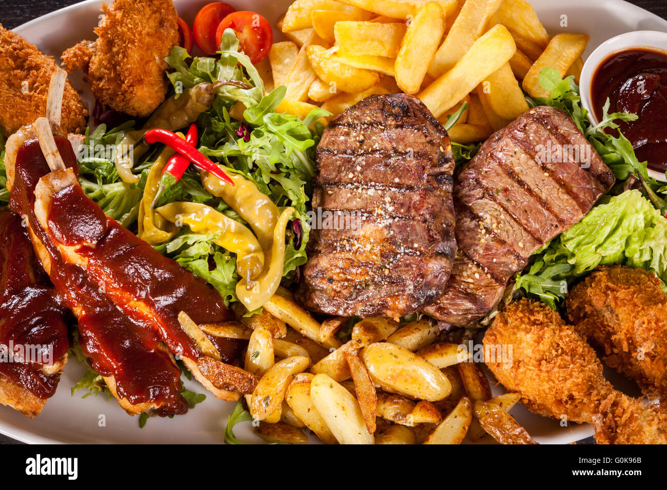 Platter of mixed meats, salad and French fries Stock Photo