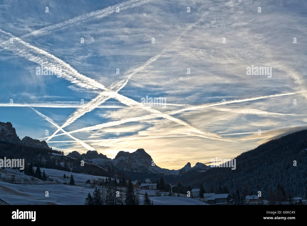 beautiful winter sunrise in the italian mountains and cloudy sky with aircraft contrails, Dolomiti Stock Photo